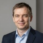Портрет уверенного российского бизнесмена с дружелюбным взглядом на нейтральном размытом фоне студии
