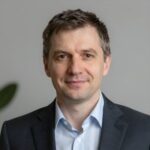 Портрет уверенного российского бизнесмена с дружелюбным взглядом на нейтральном размытом фоне студии